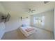 A minimalist bedroom with a ceiling fan, a window with sheer curtains, and neutral carpeting at 3719 Holly Grove Ln, Mount Dora, FL 32757