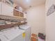 Laundry room with overhead storage cabinets, a wood shelf, and a modern washer and dryer at 3719 Holly Grove Ln, Mount Dora, FL 32757