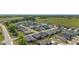 An aerial view captures a residential community with neatly arranged homes, a pond, and a green field in the background at 3786 Stephanie Way, The Villages, FL 32163