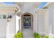 Covered front entry features a decorative front door, stylish lighting, and charming landscaping at 5835 Hensley Ave, The Villages, FL 32163