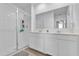 Bright bathroom featuring double sinks, tiled shower with glass door, and a large mirror at 6856 Perch Hammock Loop, Groveland, FL 34736