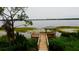 Scenic lake view featuring a wooden dock with a gazebo, surrounded by lush greenery at 6856 Perch Hammock Loop, Groveland, FL 34736