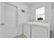 Bright laundry room with washer, dryer, storage shelf, and a window at 6856 Perch Hammock Loop, Groveland, FL 34736