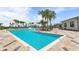 Large community pool area featuring lounge seating and splash zone, surrounded by lush landscaping and palm trees at 6856 Perch Hammock Loop, Groveland, FL 34736