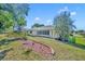 Backyard with a well-manicured lawn, mulched flowerbeds, and mature landscaping around the sunroom at 9025 Se 136Th Loop, Summerfield, FL 34491