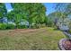 Landscaped front yard featuring vibrant green grass and mature trees under a sunny blue sky at 9025 Se 136Th Loop, Summerfield, FL 34491