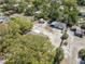 Aerial view of a residential property with a detached garage, sheds, mature trees, and a partially fenced yard at 11414 Layton St, Leesburg, FL 34788