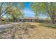 Charming single-story home featuring a well-manicured lawn, driveway, and framed by mature trees on a sunny day at 11414 Layton St, Leesburg, FL 34788