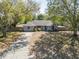 Exterior view of a single-story home with a long driveway and well-maintained front yard with established trees at 11414 Layton St, Leesburg, FL 34788