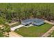 Aerial view of a modern home surrounded by a lush pine forest, showcasing its spacious lot and natural setting at 12444 Sw 76Th Ln, Dunnellon, FL 34432