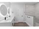 Modern bathroom featuring double sinks with backlit mirrors, a door, and a glass-enclosed shower at 12444 Sw 76Th Ln, Dunnellon, FL 34432