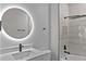 Stylish bathroom with a vanity, a backlit round mirror, matte black fixtures, and marble-tiled shower and tub at 12444 Sw 76Th Ln, Dunnellon, FL 34432