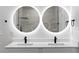Close-up of a modern bathroom vanity featuring double sinks, black fixtures, and backlit mirrors at 12444 Sw 76Th Ln, Dunnellon, FL 34432