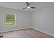 Simple bedroom with a window overlooking the greenery outside, wood floors, and modern ceiling fan at 12444 Sw 76Th Ln, Dunnellon, FL 34432