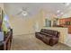 Cozy living room with vaulted ceiling, ceiling fan and comfortable leather sofa looking into kitchen at 12815 Katherine Cir, Clermont, FL 34711