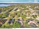 Aerial view of a residential neighborhood featuring lush greenery, single-Gathering homes, and a serene lake in the distance at 13421 Via Roma Cir, Clermont, FL 34711