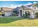 Attractive home featuring an arched entryway, mature landscaping, and an American flag display at 13421 Via Roma Cir, Clermont, FL 34711