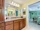 Well-lit bathroom with granite countertops, wood cabinets, and a view into the Primary bedroom at 1430 Hillstream St, The Villages, FL 32163