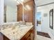 Bathroom featuring granite countertops, wooden cabinetry, and a large mirror at 1430 Hillstream St, The Villages, FL 32163