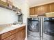 Laundry room equipped with washer, dryer, sink, storage cabinets, and shelving at 1430 Hillstream St, The Villages, FL 32163