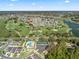 Scenic aerial view of a golf course community with a pool, tennis court, and community parking at 1726 Augustine Dr, Lady Lake, FL 32159