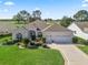 Charming one-story home featuring beautiful landscaping, a manicured lawn, and a three-car garage with easy golf course access at 1726 Augustine Dr, The Villages, FL 32159