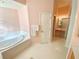 The pink-walled bathroom features a tub, large vanity, and walk-in shower, with a bright and airy feel at 1726 Augustine Dr, The Villages, FL 32159