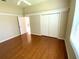 This bedroom features hardwood floors, a ceiling fan, a closet, and an open door into an adjacent space at 1726 Augustine Dr, The Villages, FL 32159