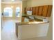 Kitchen with light-colored tile flooring, wood cabinetry, and view into casual dining area at 1726 Augustine Dr, The Villages, FL 32159