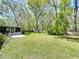 Expansive backyard featuring a screened porch, lush lawn, mature trees, and a wooden fence for added privacy at 18319 Dells Cove Rd, Groveland, FL 34736