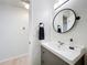 Modern bathroom with a gray vanity, white sink, oval mirror, and neutral paint at 18319 Dells Cove Rd, Groveland, FL 34736