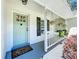 Inviting front porch featuring a light blue door, hanging plants and pretty landscaping at 18319 Dells Cove Rd, Groveland, FL 34736