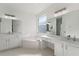 Bright bathroom featuring dual sinks, a vanity area, and a soaking tub beneath a window with natural light at 1851 Soaring Heights Cir, Orlando, FL 32837