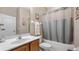 Neutral bathroom featuring an oval sink, wood cabinet, white toilet, a tub and shower combination, and decorative accents at 21046 County Road 33, Groveland, FL 34736