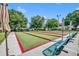 View of a bocce ball court framed by seating, shade umbrellas, and lush trees at 2205 Stonebridge Way, Clermont, FL 34711