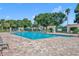 Large community swimming pool with brick pool deck surrounded by chairs and tropical landscaping at 2205 Stonebridge Way, Clermont, FL 34711