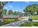 Outdoor tennis and bocce ball court bordered by lush trees and a paved walkway at 2205 Stonebridge Way, Clermont, FL 34711