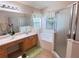 Well-lit bathroom with double sinks, vanity, shower, and tub at 24614 Stillridge Ct, Leesburg, FL 34748