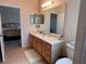 Neutral bathroom features tile flooring, wooden vanity with a countertop, and a large mirror at 24614 Stillridge Ct, Leesburg, FL 34748