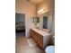 Neutral bathroom features tile flooring, wooden vanity with a countertop, and a large mirror at 24614 Stillridge Ct, Leesburg, FL 34748