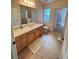 Neutral bathroom features tile flooring, wooden vanity with a countertop, and a window for natural light at 24614 Stillridge Ct, Leesburg, FL 34748