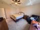 Cozy bedroom with carpet, ceiling fan, large window and classic black iron bedframe at 24614 Stillridge Ct, Leesburg, FL 34748