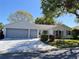 Charming single-story home featuring a two-car garage, well-manicured lawn, and mature trees at 24614 Stillridge Ct, Leesburg, FL 34748