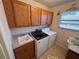 Functional laundry room with sink, oak cabinets, and washer and dryer hookups at 24614 Stillridge Ct, Leesburg, FL 34748