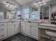 Bright bathroom featuring double vanity, white cabinetry, and a makeup station with a comfortable stool at 2922 Rain Lily Loop, The Villages, FL 32163