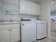 Functional laundry room with sink, storage cabinets, and modern washer and dryer units at 2922 Rain Lily Loop, The Villages, FL 32163