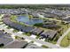 Aerial view of a residential neighborhood featuring single-Gathering homes around a pond and lush greenery at 3334 Pierluissi Path, The Villages, FL 32163