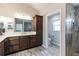 Well-lit bathroom featuring a double sink vanity with quartz countertops, wood cabinets, and a glass enclosed shower at 3334 Pierluissi Path, The Villages, FL 32163