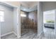 Stylish bathroom with a stand-up shower featuring pebble floors and wood-look tile at 3334 Pierluissi Path, The Villages, FL 32163