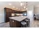 Modern kitchen featuring a large island with seating, dark wood cabinetry, and stainless steel appliances at 3334 Pierluissi Path, The Villages, FL 32163